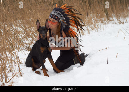 Mädchen in Indianer Kopfschmuck mit Doderman Pinscher Stockfoto