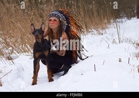 Mädchen in Indianer Kopfschmuck mit Doderman Pinscher Stockfoto