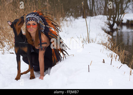 Mädchen in Indianer Kopfschmuck mit Doderman Pinscher Stockfoto