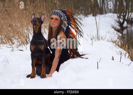 Mädchen in Indianer Kopfschmuck mit Dobermann Stockfoto