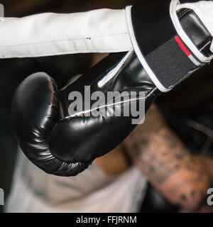 Schwarz Boxhandschuh Linked Ring Seile und Boxers tätowierten Arm im Hintergrund Stockfoto