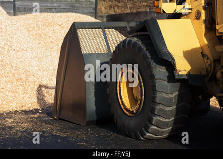 Brakne-Hoby, Schweden-7. Februar 2016: Eine gelbe Volvo BM Frontlader mit Schaufel nach unten laden Biokraftstoff aus einem Haufen von Hackschnitzel Stockfoto