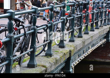 Nahaufnahme von Fahrrädern sind gesperrt, um das Geländer einer Brücke über die Grachten in Amsterdam. Stockfoto