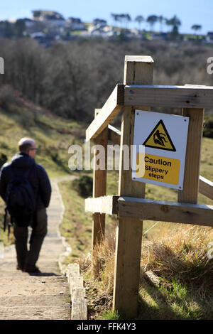 "Vorsicht rutschig Schritte" melden Sie an der Spitze der steilen Stufen aus Holzschwellen, mit einem Mann sie absteigend gemacht. Stockfoto