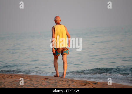 Älterer Mann zu Fuß am Meer am Ende des Tages Stockfoto