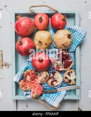 Rote und weiße Granatäpfel und Messer auf Küchentuch in blaue Fach über leichte bemalte hölzerne Kulisse, Draufsicht Stockfoto