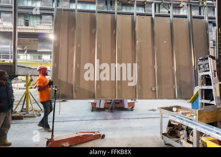 Arbeiter Manöver eine Wand im Ort für modulare Gehäuse in einer Fabrik in Brooklyn Navy Yard in New York auf Donnerstag, 11. Februar 2016. Wegen der steigenden Mieten und die Notwendigkeit für einen speziellen Raum wird nach diesem Job, Gehäuse für die Nehemia Spring Creek-Entwicklung die Fabrik nach Schließung. Steiner Studios, nimmt einen anderen Mieter im Brooklyn Navy Yard über den Raum. (© Richard B. Levine) Stockfoto