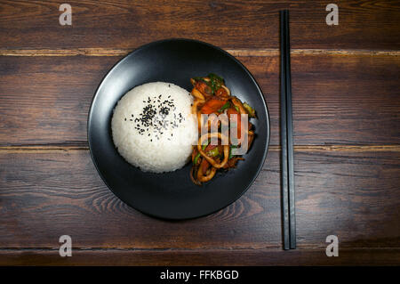 Koreanische Teller Reis mit gebratener Tintenfisch in scharfer Sauce mit Stäbchen Draufsicht Stockfoto
