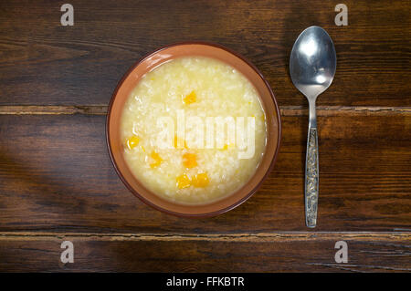 Reisbrei mit Kürbis auf dem Holztisch mit Löffel Stockfoto