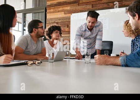 Junges Unternehmen Team in einer Besprechung, die Fortschritte des Unternehmens zu diskutieren. Kreativ-Profis sitzen um einen Tisch im Büro. Stockfoto