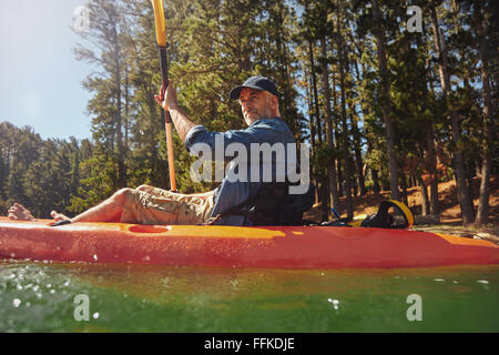 Porträt eines älteren Mannes mit Kajak in einem See. Kaukasischen Mann paddeln eine Kajak an Sommertag. Stockfoto