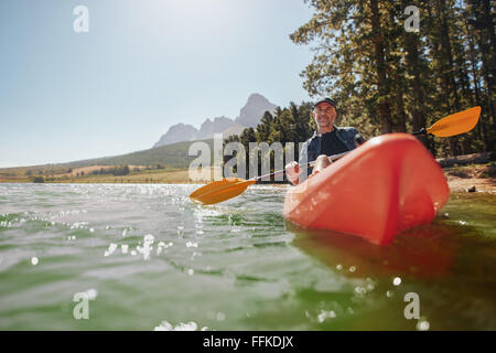 Rückansicht eines senior Mannes an einem sonnigen Tag in einem See paddeln. Senior woman paddeln Kajak. Stockfoto