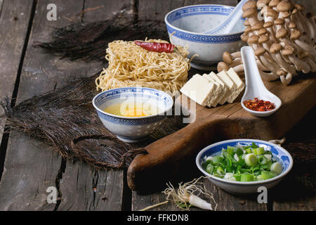 Zutaten für asiatische Ramen-Suppe. Nudeln, Frühlingszwiebeln, Feta-Käse, Champignons, Ei und Paprika in asiatischen Anemonen-Schalen ov Stockfoto