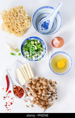 Zutaten für asiatische Ramen-Suppe. Nudeln, Frühlingszwiebeln, Feta-Käse, Champignons, Ei und Paprika in asiatischen Anemonen-Schalen ov Stockfoto