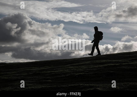 Eine einsame weibliche Wanderer Silhouette gegen ein bewölkter Himmel. Stockfoto