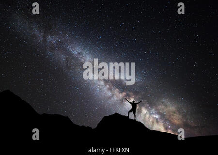 Landschaft mit Milky Way. Nachthimmel mit Sternen und Silhouette des ständigen glücklich mit oben erhobenen Armen auf dem Berg. Stockfoto