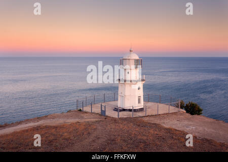 Schönen alten weißen Leuchtturm an der Küste Ozean auf dem Berg bei Sonnenuntergang. Sommer-Seenlandschaft Stockfoto