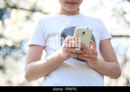 Mädchen mit Handy. Das Kind sendet Sms... Das Kind verwendet eine Anwendung auf Ihrem Handy Stockfoto