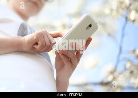 Mädchen mit Handy. Das Kind sendet Sms... Das Kind verwendet eine Anwendung auf Ihrem Handy Stockfoto