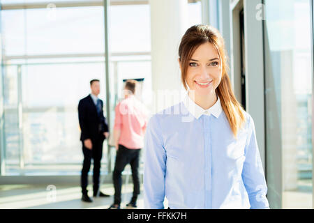 Gut gekleidete Geschäftsfrau mit Kollegen im Hintergrund Stockfoto