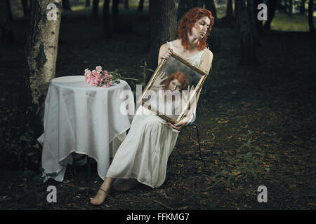 Seele einer Frau gefangen in einem Spiegel in einem seltsamen Wald. Dunkel und surreal Stockfoto