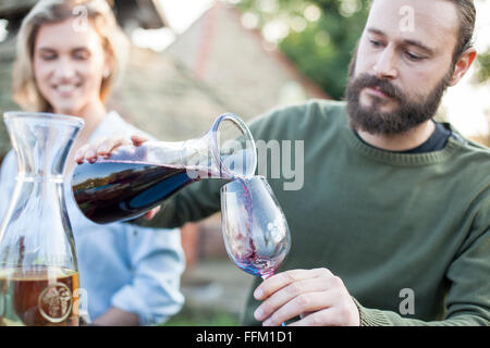 Man gießt Rotwein auf der Gartenparty Stockfoto