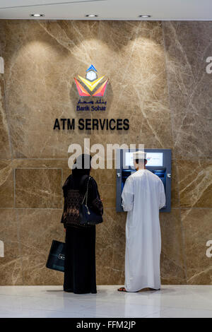 Eine omanische paar an einem Geldautomaten im Wege Shopping-Mall, Muscat, Sultanat Oman Oman Stockfoto