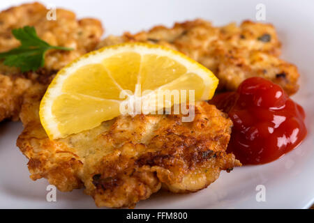 Golden gebratenen Schnitzel oder Schnitzel mit einer Beilage von Ketchup oder Tomaten-Sauce, serviert mit einer Scheibe Zitrone Stockfoto