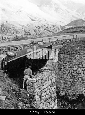 Ein Mann inspiziert ein abgestürztes Auto auf eine Hochalpenstraße in der Schweiz in den 1950er Jahren. Stockfoto