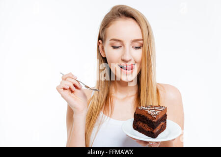 Attraktive verspielte junge Frau halten und Essen Stück Schokoladenkuchen auf weißem Hintergrund Stockfoto