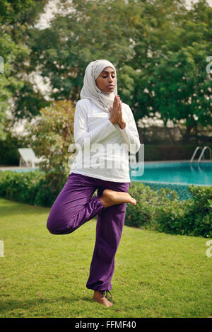 Muslimische Frau beim Yoga am Pool Stockfoto