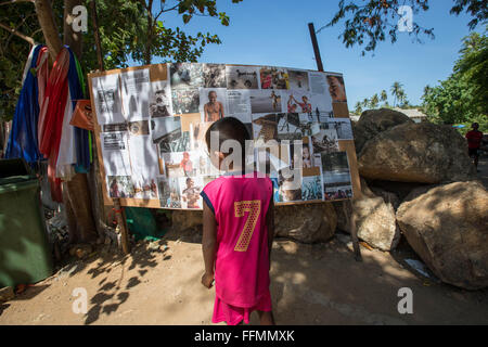 Phuket, Rawai Beach, Thailand. 14. Februar 2016. Ein Kind stehen am Eingang des Dorfes Meer Zigeuner, wie die Bewohner auf Zeitungspapier halten Artikel eine Weile nach dem Angriff. Tätlichen Angriffs brach am Morgen des 27. Januar 2016 am Rawai Beach in Chao Lay Indianerdorf (Seezigeuner), mindestens 100 Männer wurden durch ein video-Aufnahmen gesehen, schlagen mit Holzstöcken, Stanzen und treten die Seezigeuner über eine 33 Rai (ca. 5 ha) erstrecken sich von Land, zumindest mehr als 30 Seezigeuner verletzt und einige Angeln Ausrüstungen wurden zerstört sowie Häuser. Das Land ist im Besitz von "Baron Stockfoto