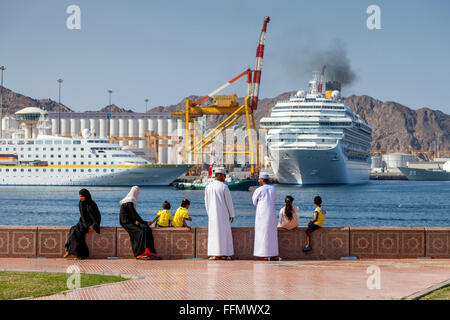 Eine omanische Familie sehen Sie die Kreuzfahrtschiffe Auslaufen aus dem Hafen in Muttrah, Muscat, Sultanat von Oman Stockfoto