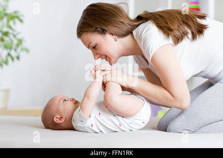 fröhliche Mutter spielen und Turnen ihr Baby Kleinkind Stockfoto