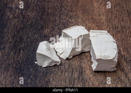 Zerbröckelte Hefe Würfel auf ein Holz Küchentisch Stockfoto