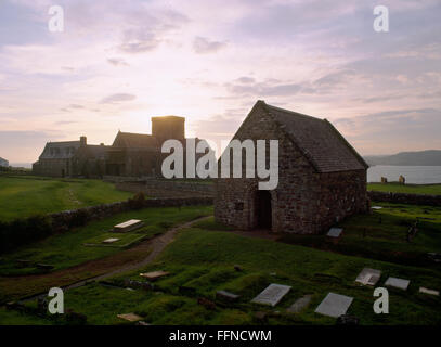 Sonnenaufgang über Iona Abbey Kirchturm, C12th St. Oran's Chapel & Reilig Odhráin Beerdigung Boden (R) & gepflasterte Straße der Toten (L). Stockfoto