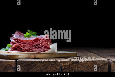 Scheiben Salami (Tiefenschärfe) auf einem alten Holztisch vintage Stockfoto