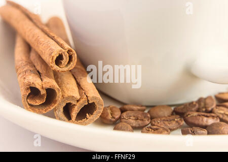 Nahaufnahme von duftenden Zimt sticks, Kaffeebohnen und weiße Tasse. Selektiven Fokus. Stockfoto