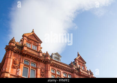 Vor ein altes Gebäude aus rotem Backstein und prunkvollen Mauerwerk. die Fassade eines historischen Gebäude und Dach mit blauem Himmel für Kopie Stockfoto