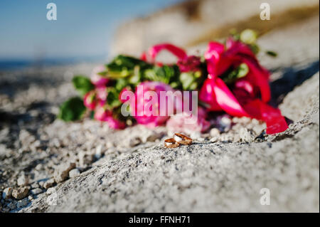 Handgemachte Hochzeit Kranz mit roten Bändern und Ringen auf Stein Felsen Stockfoto