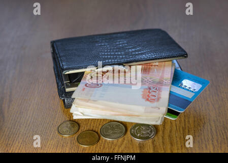 Geldbörse mit Kreditkarten und Bargeld auf einem Holztisch liegend Stockfoto