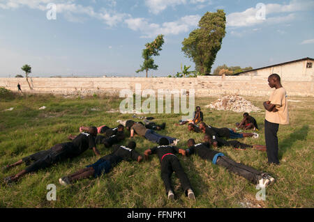 Der Leiter der Einav Levy-Delegation von Natan International Humanitarian Aid nahm an einer körperlichen Übung mit einer Gruppe haitianischer Männer Teil, die als Sicherheitsbeamte des provisorischen Lagers für Überlebende eines Erdbebens der Stärke 7,0 ausgebildet wurden, das Haiti am 12. Januar 2010 am Stadtrand von Port-au-Prince heimsuchte Stockfoto
