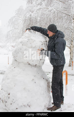 Großer Mann wirklich hohen Schneemann während massive Schneesturm Stockfoto