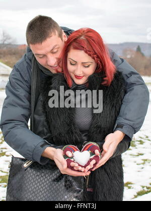 Glückliches Paar hält eine Schnee geformte Herz im freien Stockfoto