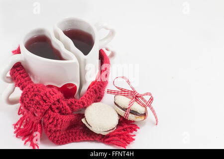 Becher mit Tee mit einem roten Schal in Herzform Stockfoto