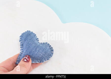 Denim-Herz in Frauenhand gegen ein Cloud-design Stockfoto