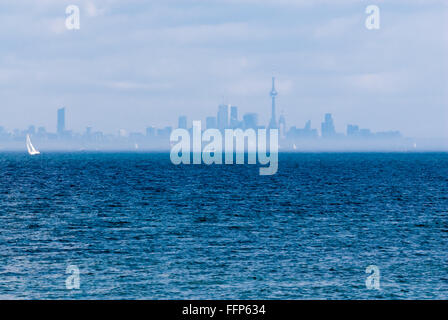 Toronto City Skyline aus ganz blaue Wellenlinie Rippled Wasser mit Segelboot und andere Boote in Entfernung in dunstiger Nebel. Stockfoto