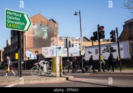 Hipster Radfahrer Überqueren der Straße an einer belebten Kreuzung in der Nähe von Hoxton Square in Shoreditch, Heimat einer großen hipster Gemeinschaft. Stockfoto