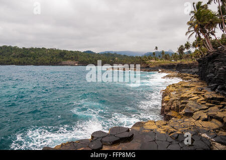 Klippen an einem tropischen Strand mit Palmen und makellosen blauen Meer. Boca do Inferno, Sao Tome und Principe. Stockfoto