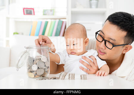 Asiatische Familie Lifestyle zu Hause. Vater und Baby Geld Glas, finanzielle Planungskonzept Münzen Inbetriebnahme. Stockfoto